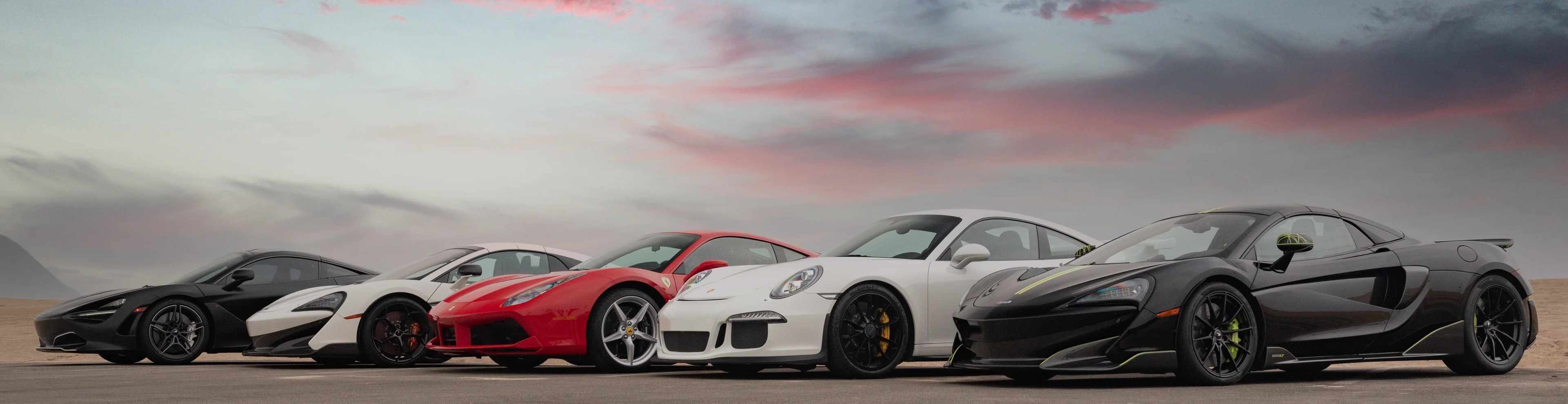 Mclarens, a Ferrari, and Porsche from luxury car company Motorenn’s inventory parked along the beach